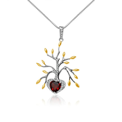 Pendant necklace featuring a tree-like silver structure with yellow leaf details and a heart-shaped red gemstone.

