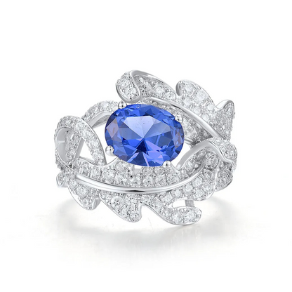 Silver ring with fern-like design, white pavé stones, and deep blue oval gemstone

