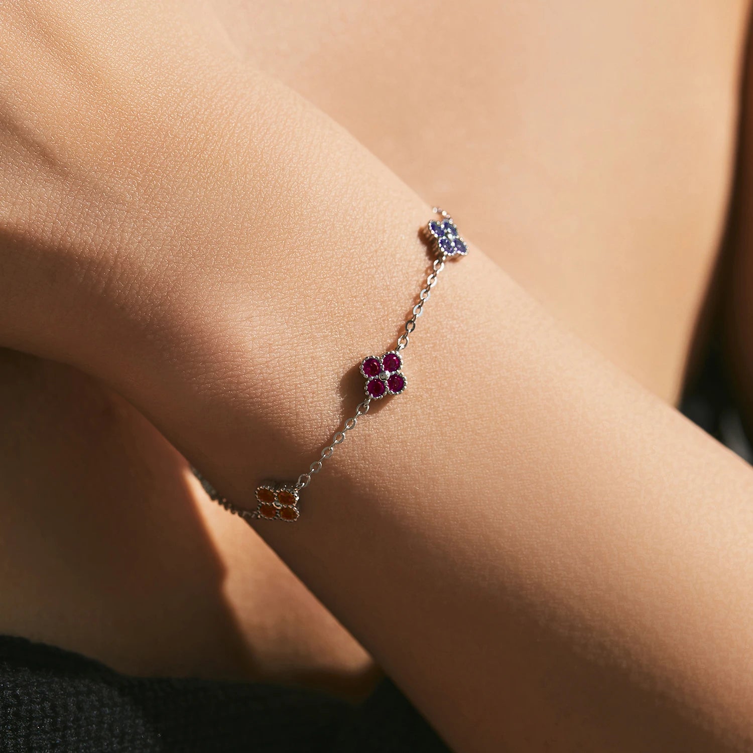 Silver bracelet with multicoloured gemstone clusters in floral shapes.

