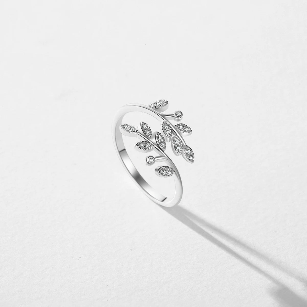 Silver ring designed with two curved branches, each adorned with pavé-set leaf shapes and tiny round white stones.

