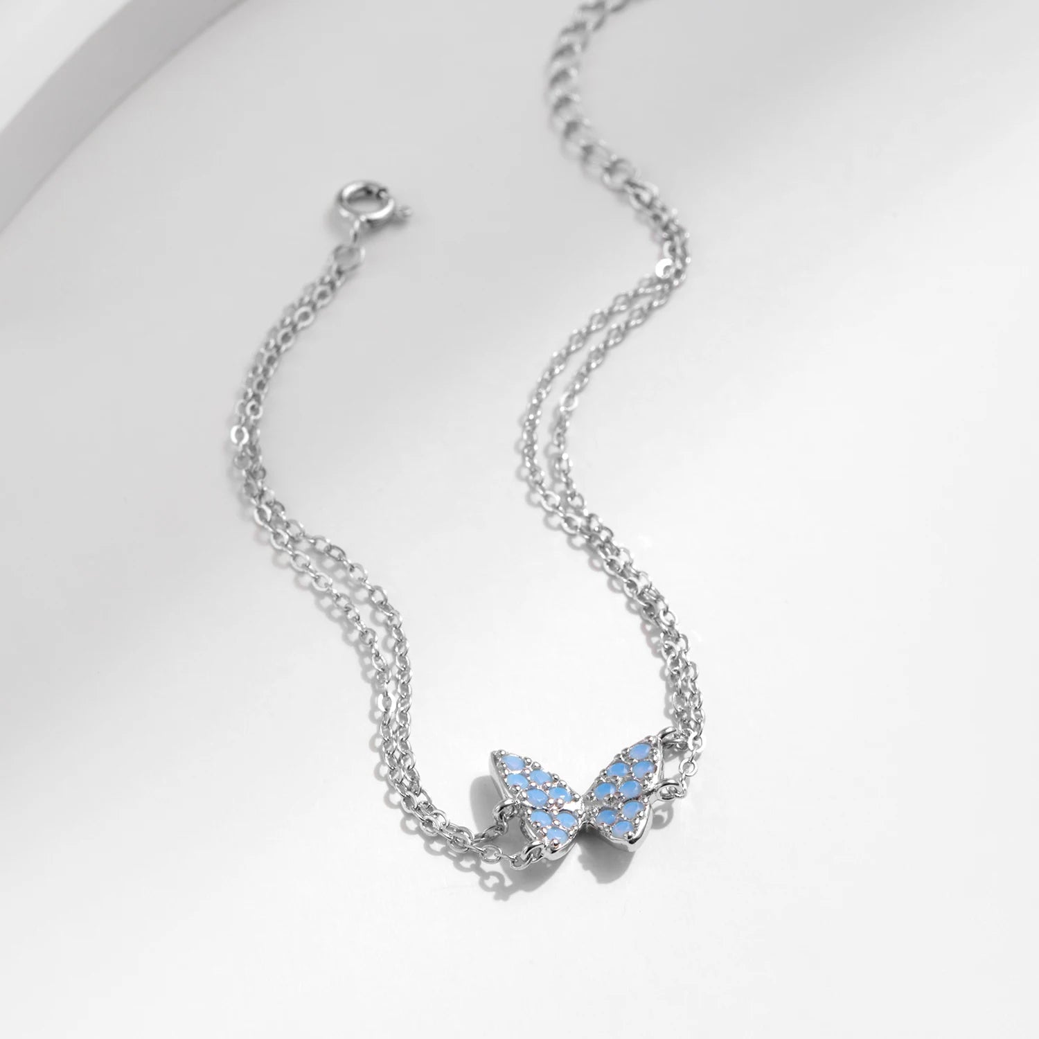 Delicate silver bracelet with a central opal butterfly charm and fine double chain

