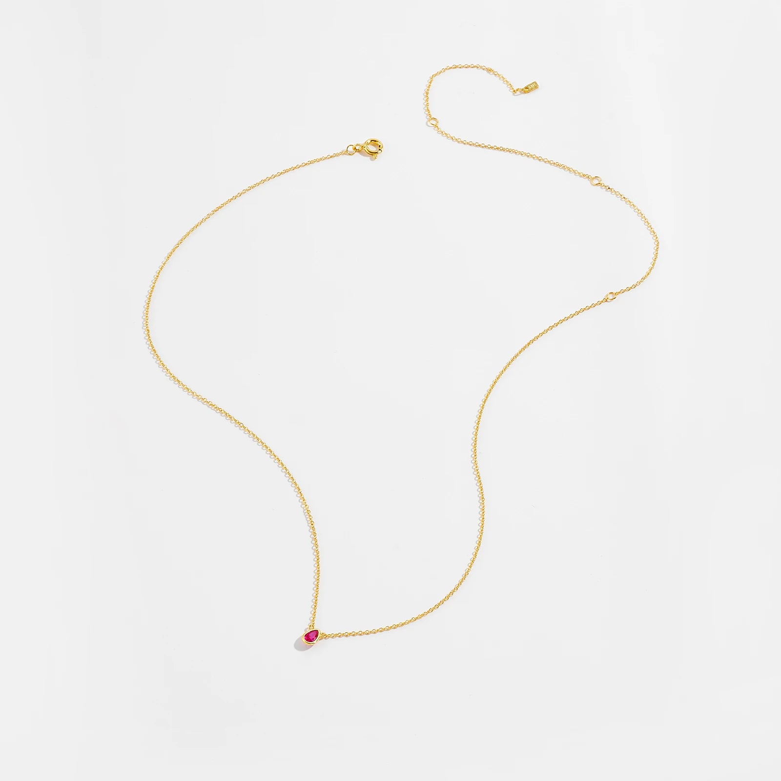 Gold necklace with a pear-shaped pink gemstone pendant at the center.

