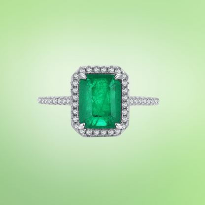 Rectangular green gemstone ring with a halo of clear stones on a silver band.

