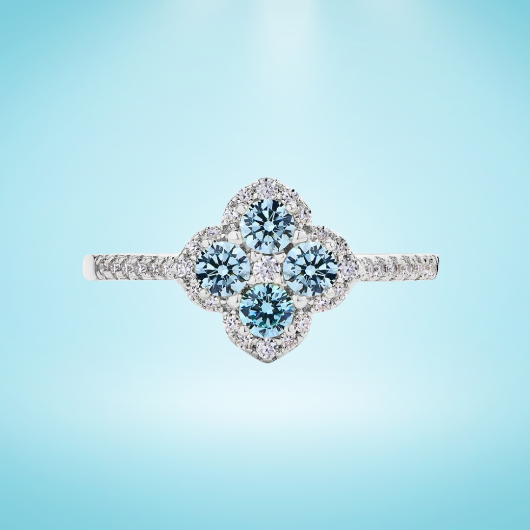 Sterling silver ring with four clustered round aquamarine-blue stones in a floral clover shape, surrounded by pavé-set crystals, on a light blue background
