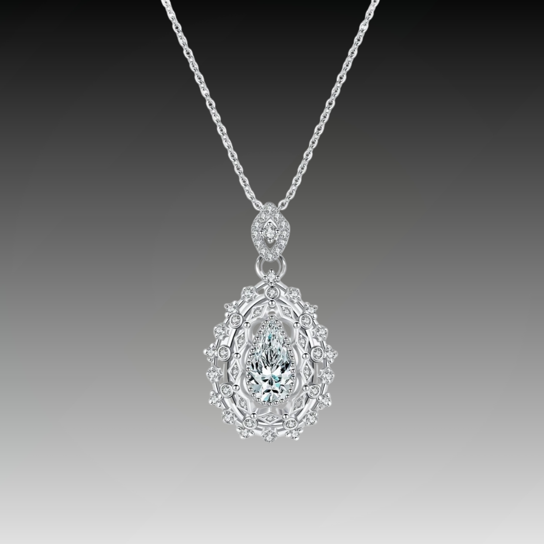 Ornate silver necklace with an intricate teardrop pendant, featuring a central pear-cut white gemstone, part of the Bianco Nero collection.

