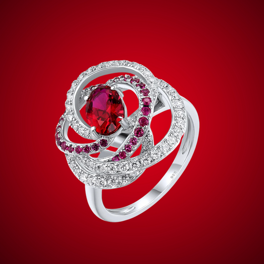 Vermiglio ring with a vivid red oval gemstone at the center, wrapped in spiraling bands of white and red stones set in silver.

