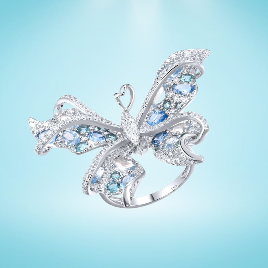 Silver butterfly-shaped ring with shimmering light blue and aqua gemstones set in detailed wing patterns

