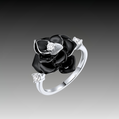 Silver ring with a black enamel rose centerpiece and two clear gemstones on the band.

