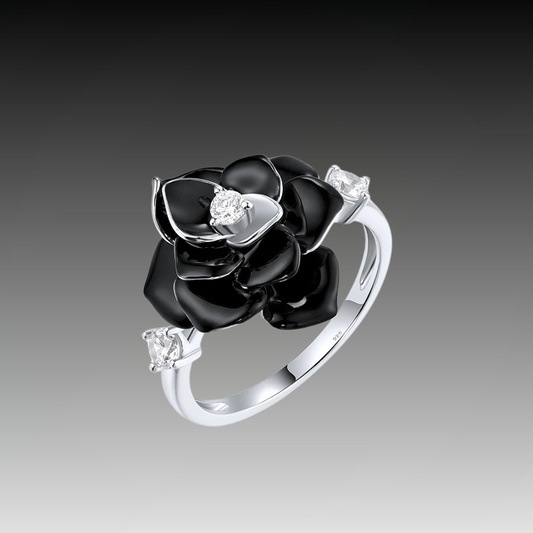 Silver ring with a black enamel rose centerpiece and two clear gemstones on the band.

