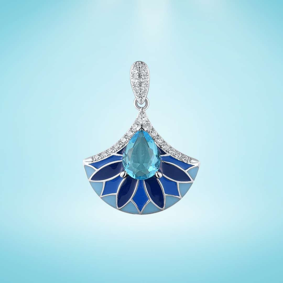 Sterling silver pendant with a teardrop-shaped aqua blue gemstone above a fan-shaped design of layered navy and cobalt enamel petals, framed by pavé stones, on a light blue background