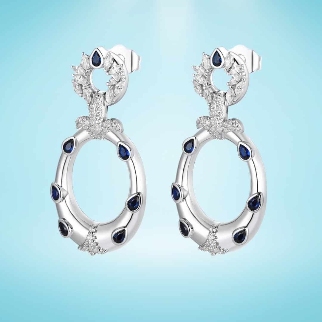 Sterling silver hoop earrings with blue teardrop stones and pavé crystal accents, inspired by underwater textures, displayed on a light blue background