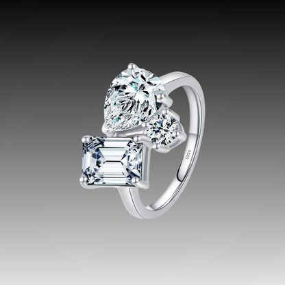 Silver ring with a mix of emerald, pear, and round-cut clear stones in an asymmetrical setting

