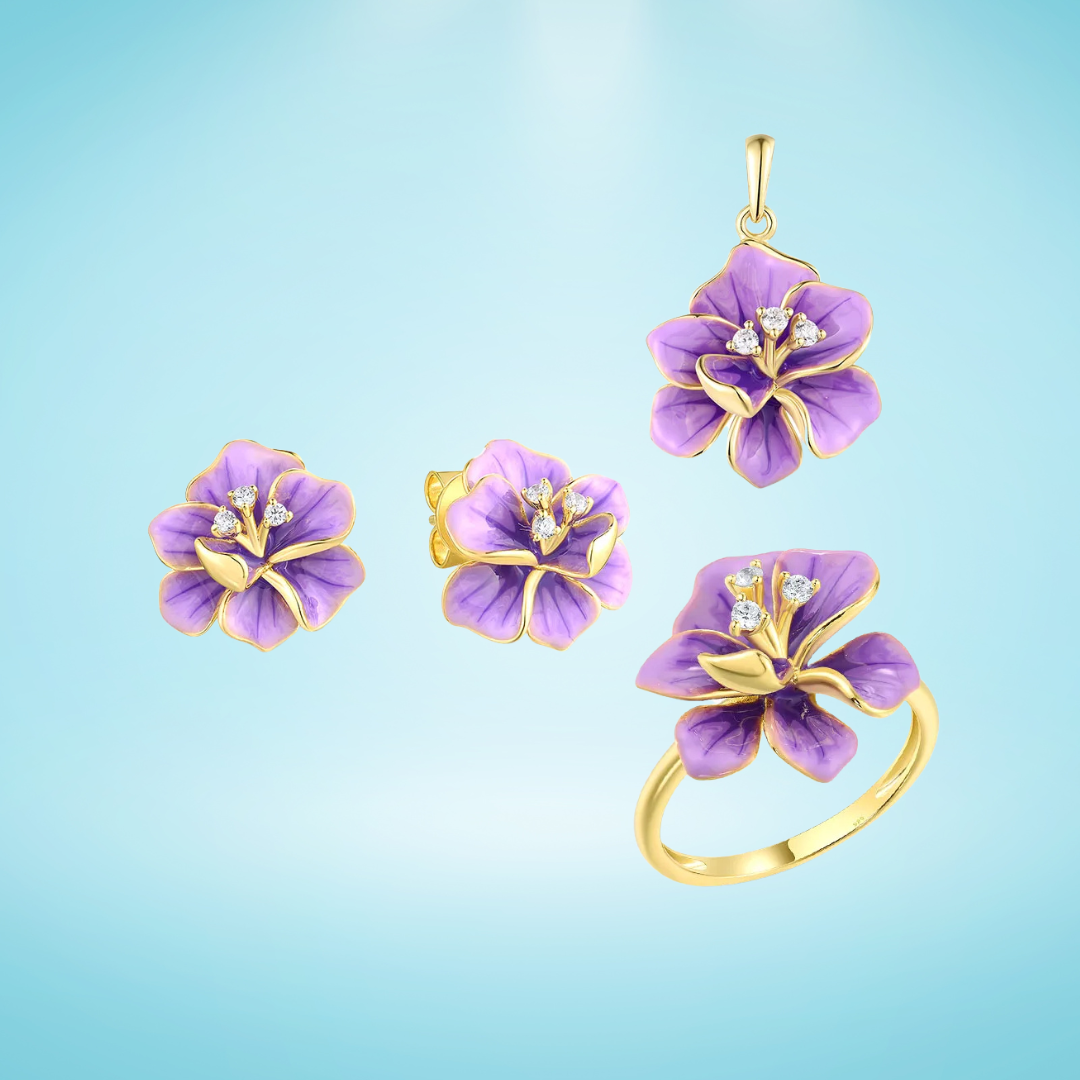 Gold floral jewelry set with violet enamel flowers and crystal accents, including earrings, pendant, and ring, on a light blue background

