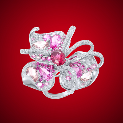 Lalicata ring shaped like an abstract floral design, adorned with pink and red gemstones set in polished silver.

