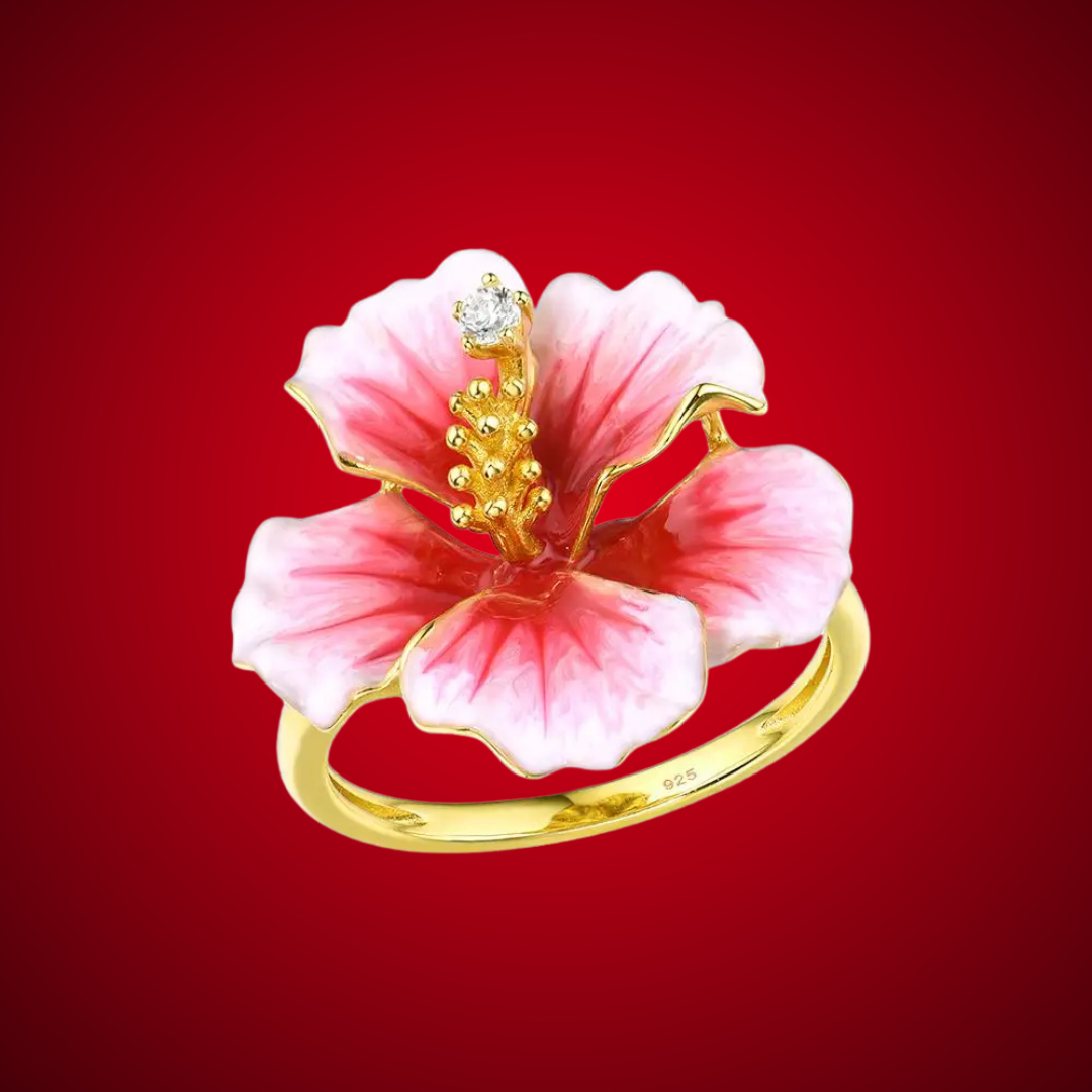 Prato ring shaped like a blooming hibiscus flower in pink enamel with golden stamen and a single sparkling white stone.

