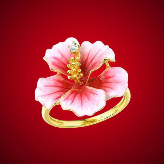 Prato ring shaped like a blooming hibiscus flower in pink enamel with golden stamen and a single sparkling white stone.

