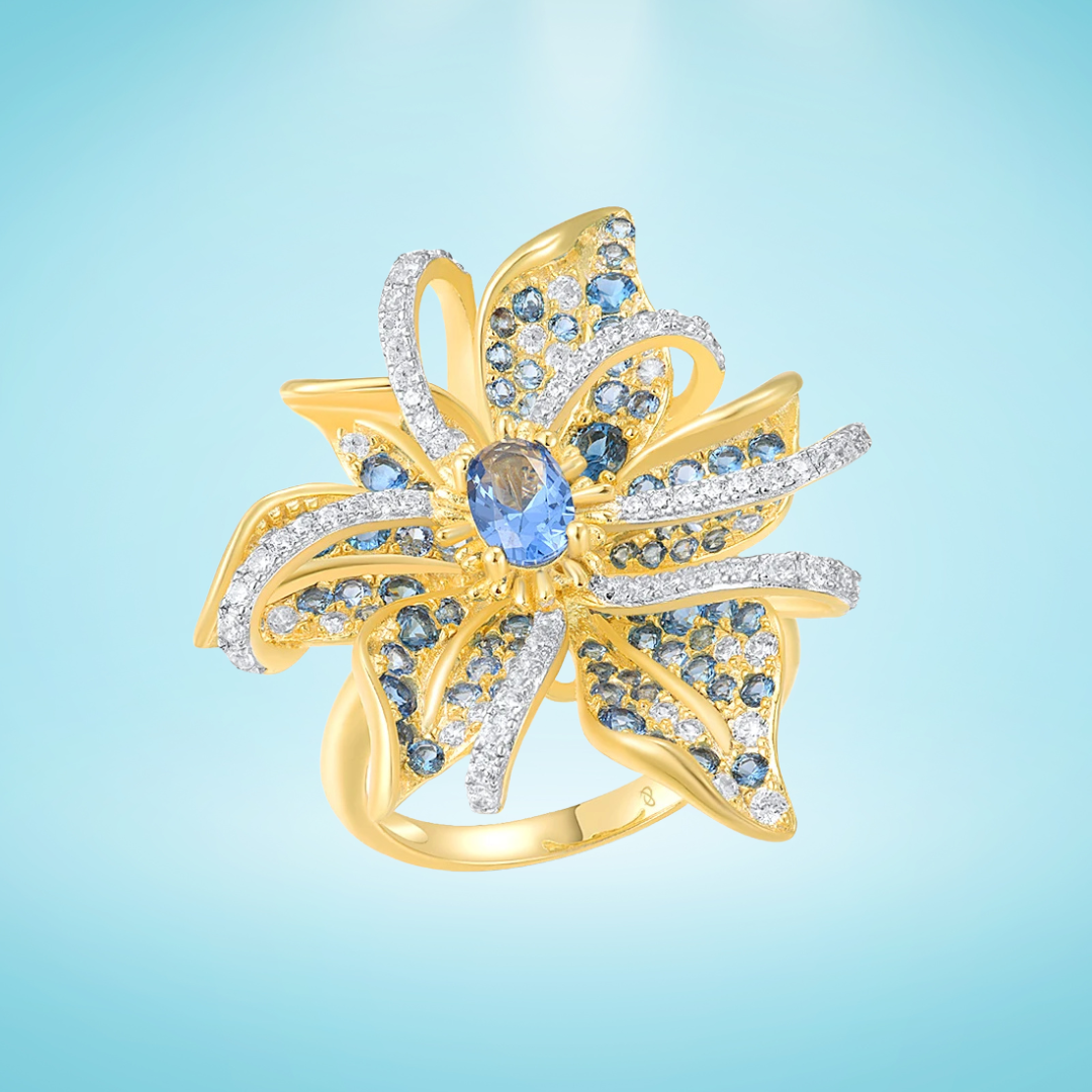 Gold ring in the shape of a flower with pavé blue and white stones and a central oval gem

