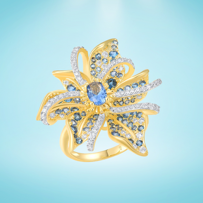 Gold ring in the shape of a flower with pavé blue and white stones and a central oval gem

