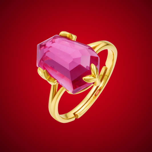 Gold ring with a bold, faceted pink gemstone held by petal-shaped prongs, displayed on a red background.

