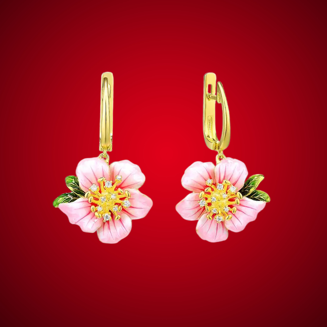 Prato earrings featuring soft pink flower petals, golden centers with crystal accents, and green enamel leaves.

