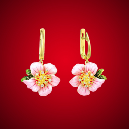 Prato earrings featuring soft pink flower petals, golden centers with crystal accents, and green enamel leaves.

