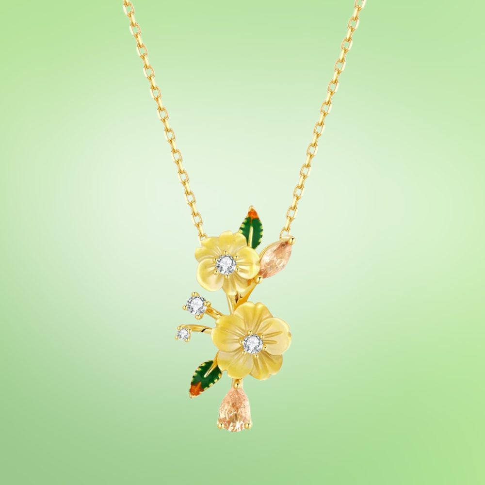 Yellow flower pendant necklace with gemstone accents and green enamel leaf details

