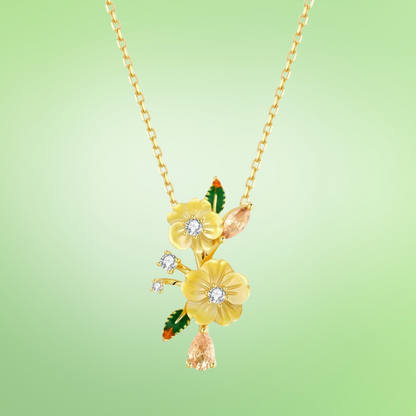 Yellow flower pendant necklace with gemstone accents and green enamel leaf details

