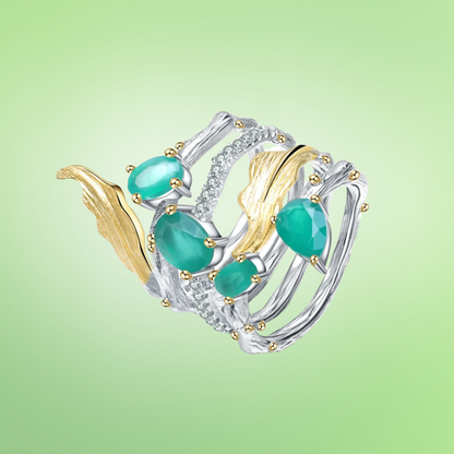 Multi-band silver ring with green gemstones, gold leaf accents, and intricate vine-like detailing

