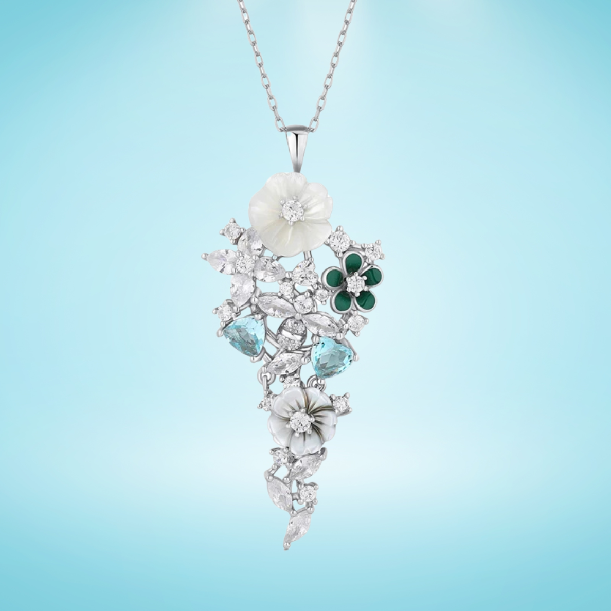 Pendant featuring carved mother-of-pearl flowers, green enamel petals, and aquamarine-blue stones set in silver with white zircon accents.

