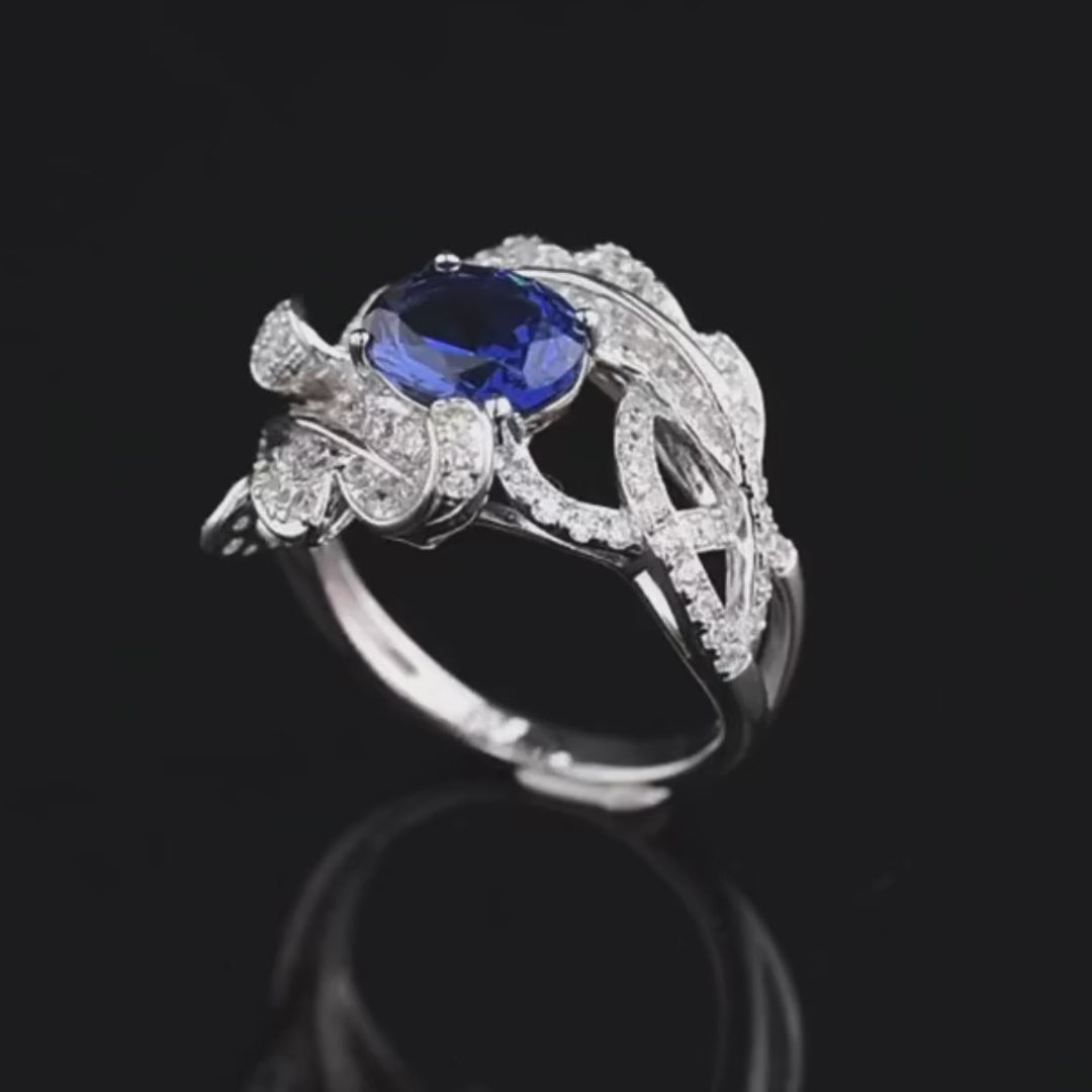 Silver ring with fern-like design, white pavé stones, and deep blue oval gemstone


