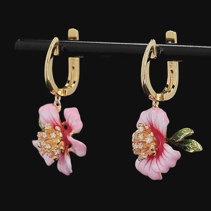 Prato earrings featuring soft pink flower petals, golden centers with crystal accents, and green enamel leaves.

