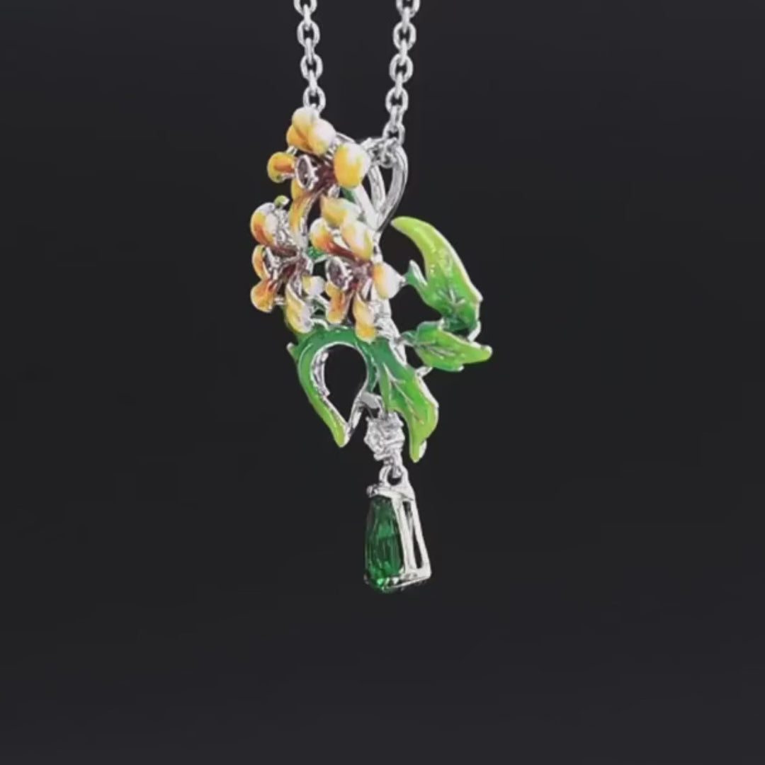 Brooch with three yellow enamel flowers, green enamel leaves, and a dangling green teardrop gemstone

