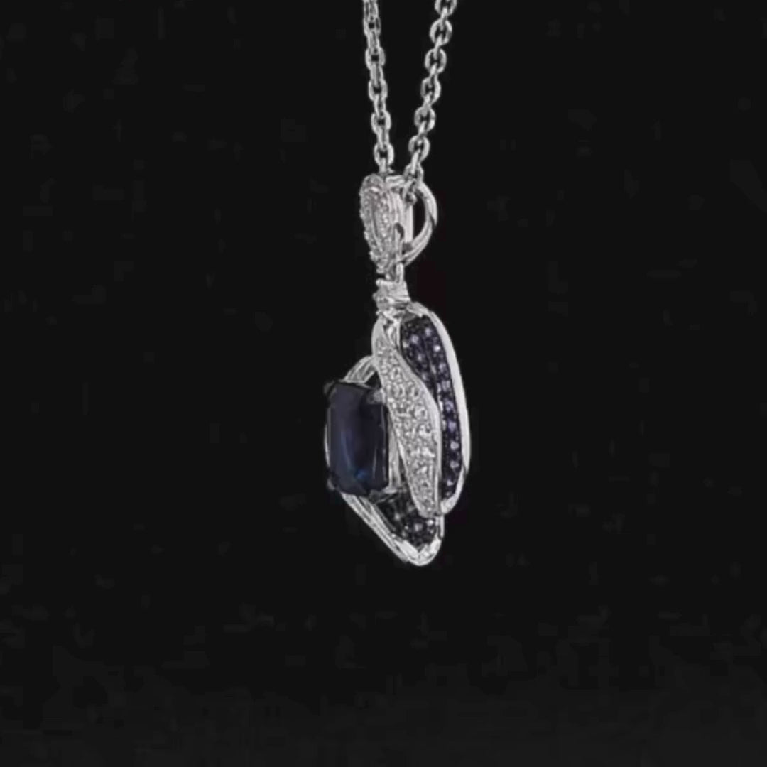 Sterling silver pendant with a rectangular dark blue gemstone surrounded by curving pavé-set bands and clustered blue stones