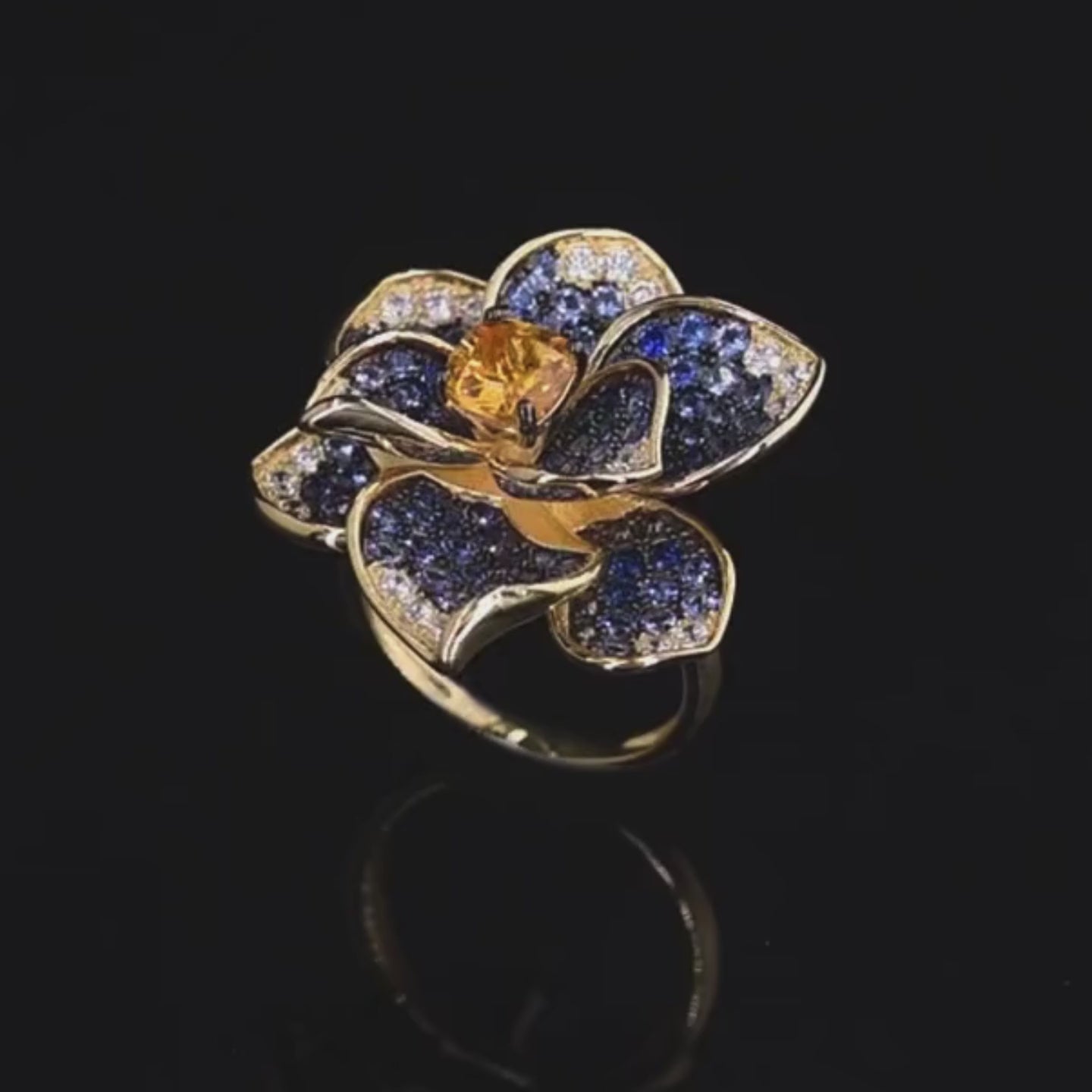 Statement floral ring in gold plating, with deep blue and clear pavé stones and a golden-yellow center gem

