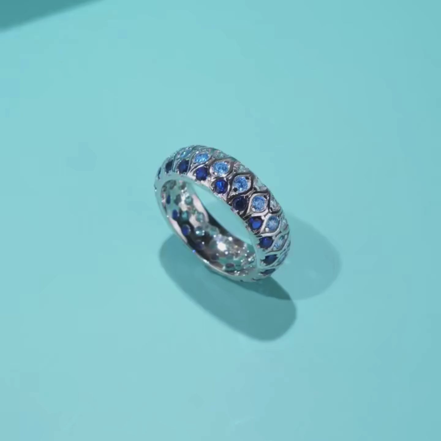 Sterling silver eternity band with alternating light and dark blue stones in a woven design

