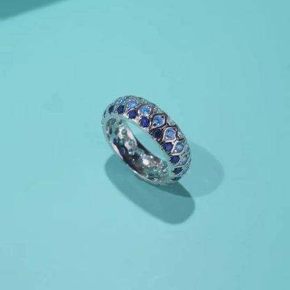 Sterling silver eternity band with alternating light and dark blue stones in a woven design

