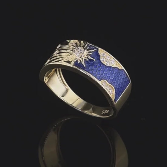 Gold-plated silver ring with a radiant sunburst design, sparkling stones, and deep blue enamel detailing

