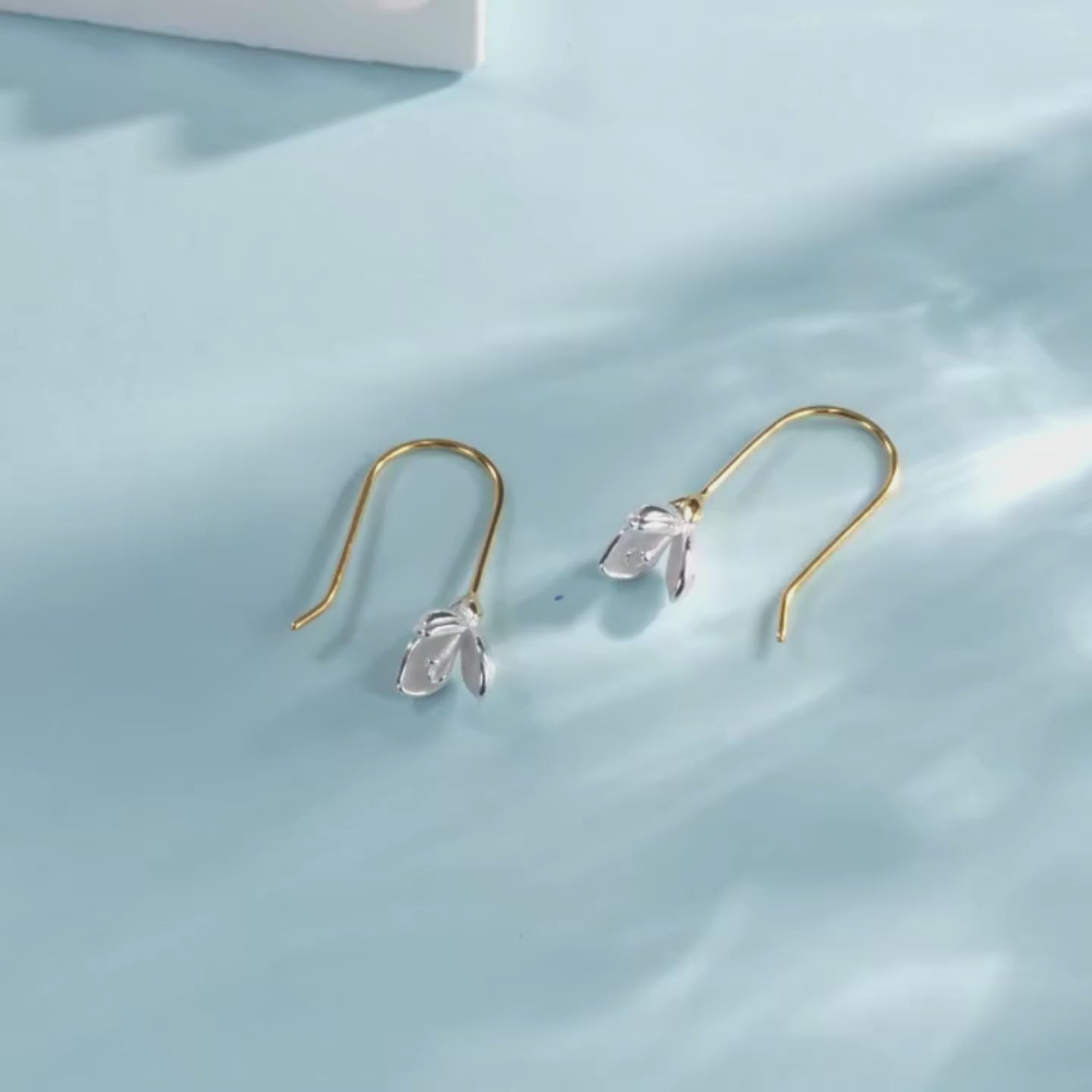Gold hook earrings with delicate silver flower bud drops.

