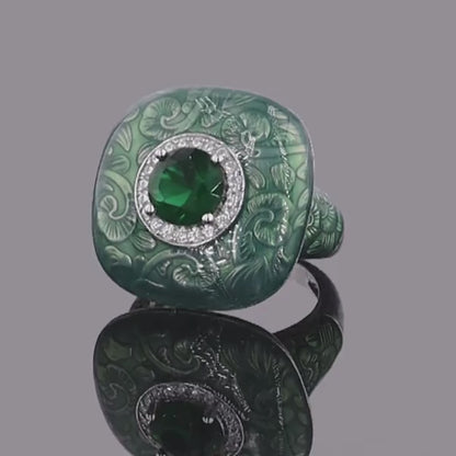 Square green enamel ring with engraved floral design and central green gemstone

