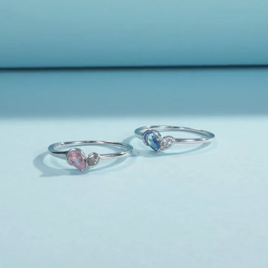 Sterling silver ring with a pear-shaped blue stone and round white stone set side by side
Sterling silver ring featuring a pink teardrop stone paired with a round clear stone in an open-heart inspired setting.


