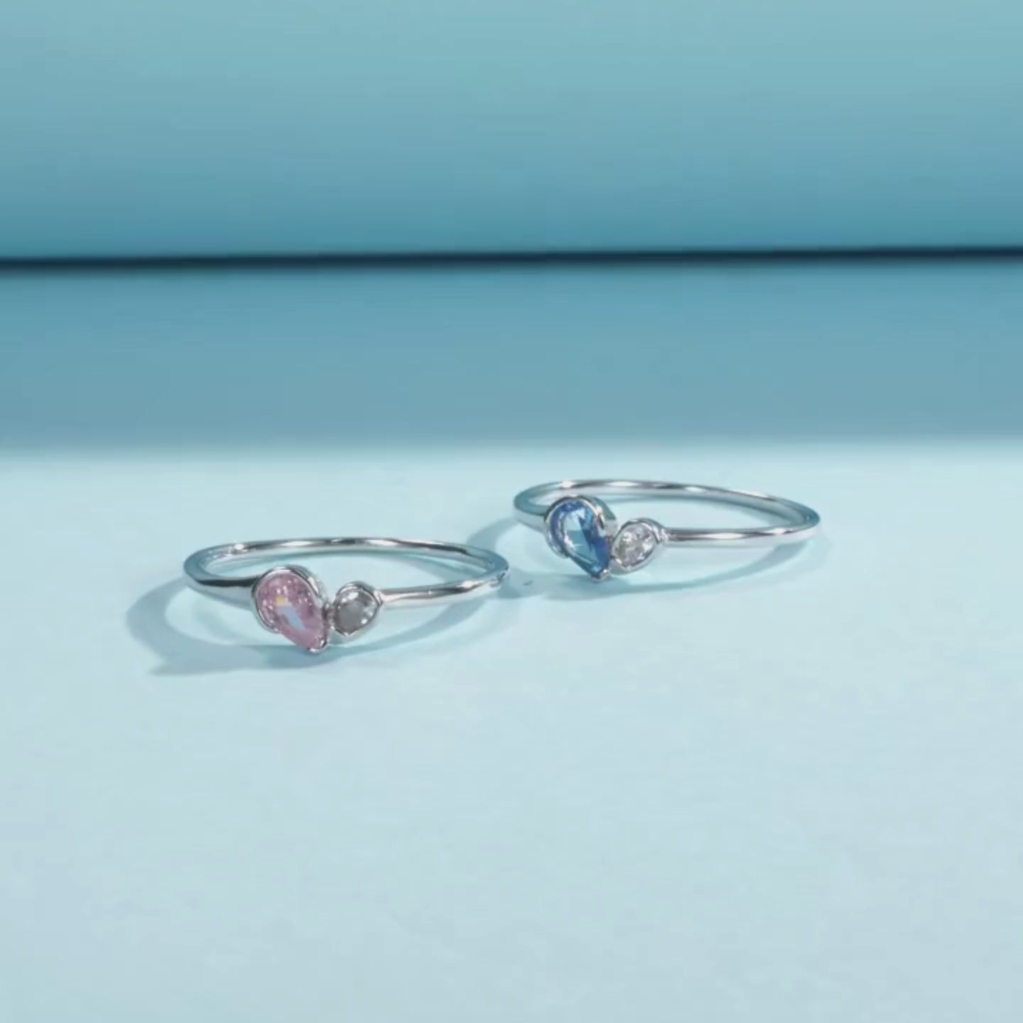 Sterling silver ring with a pear-shaped blue stone and round white stone set side by side
Sterling silver ring featuring a pink teardrop stone paired with a round clear stone in an open-heart inspired setting.


