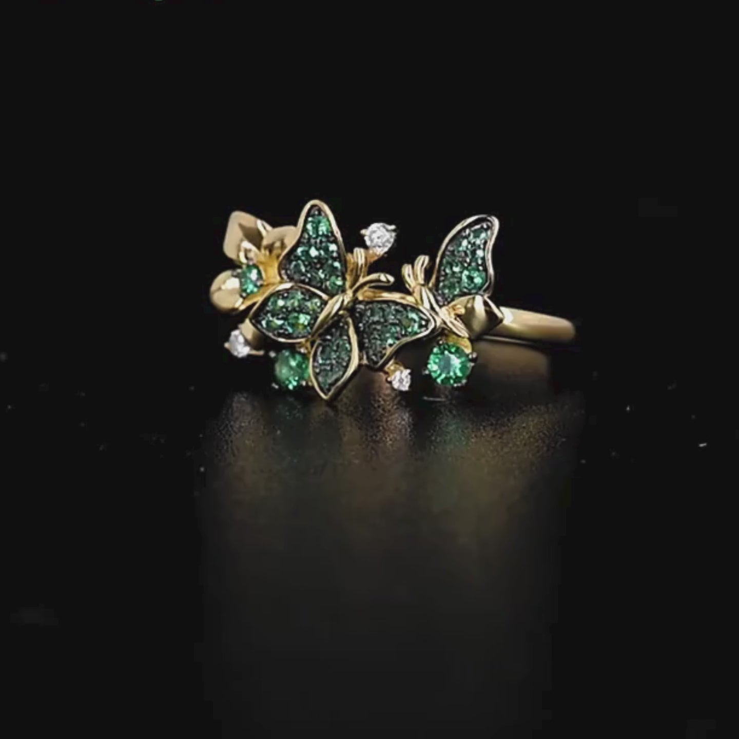 Gold butterfly ring adorned with green crystals and delicate flower accents

