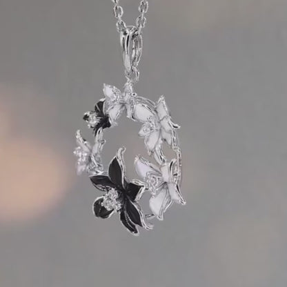 Pendant with alternating black and white floral elements arranged in a circular wreath

