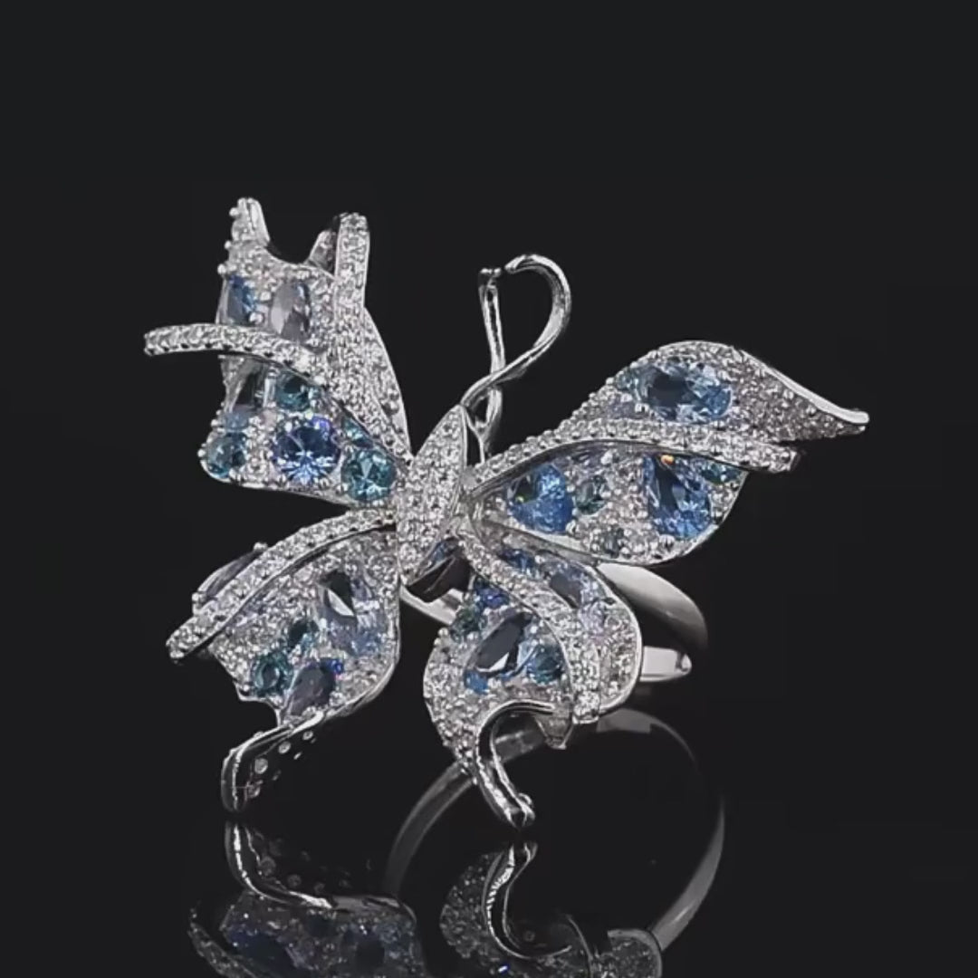 Silver butterfly-shaped ring with shimmering light blue and aqua gemstones set in detailed wing patterns

