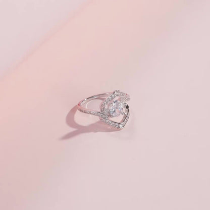 Silver ring with a central round white stone encircled by two asymmetrical open square-shaped bands encrusted with smaller stones.

