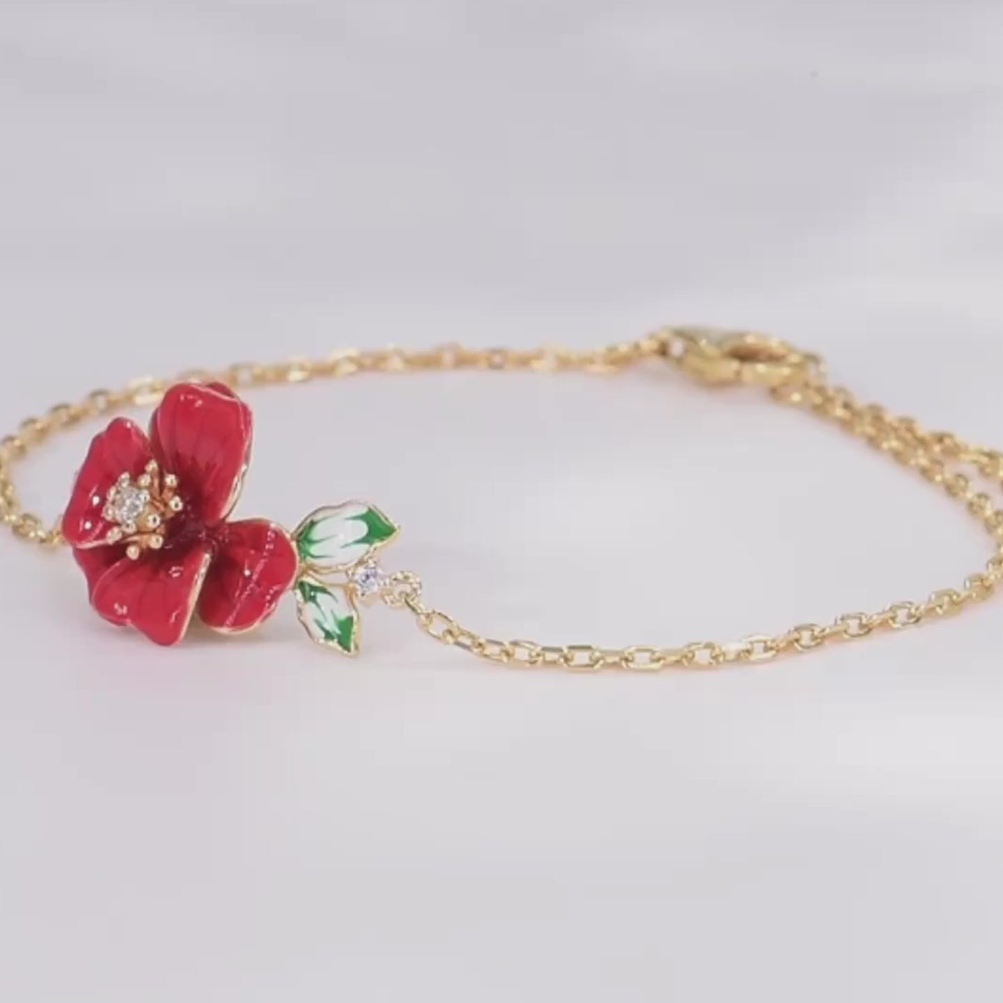 Delicate gold bracelet featuring a red enamel flower with a crystal center and green-and-white enamel leaves, Rosa Rossa from the Rossa Collection.

