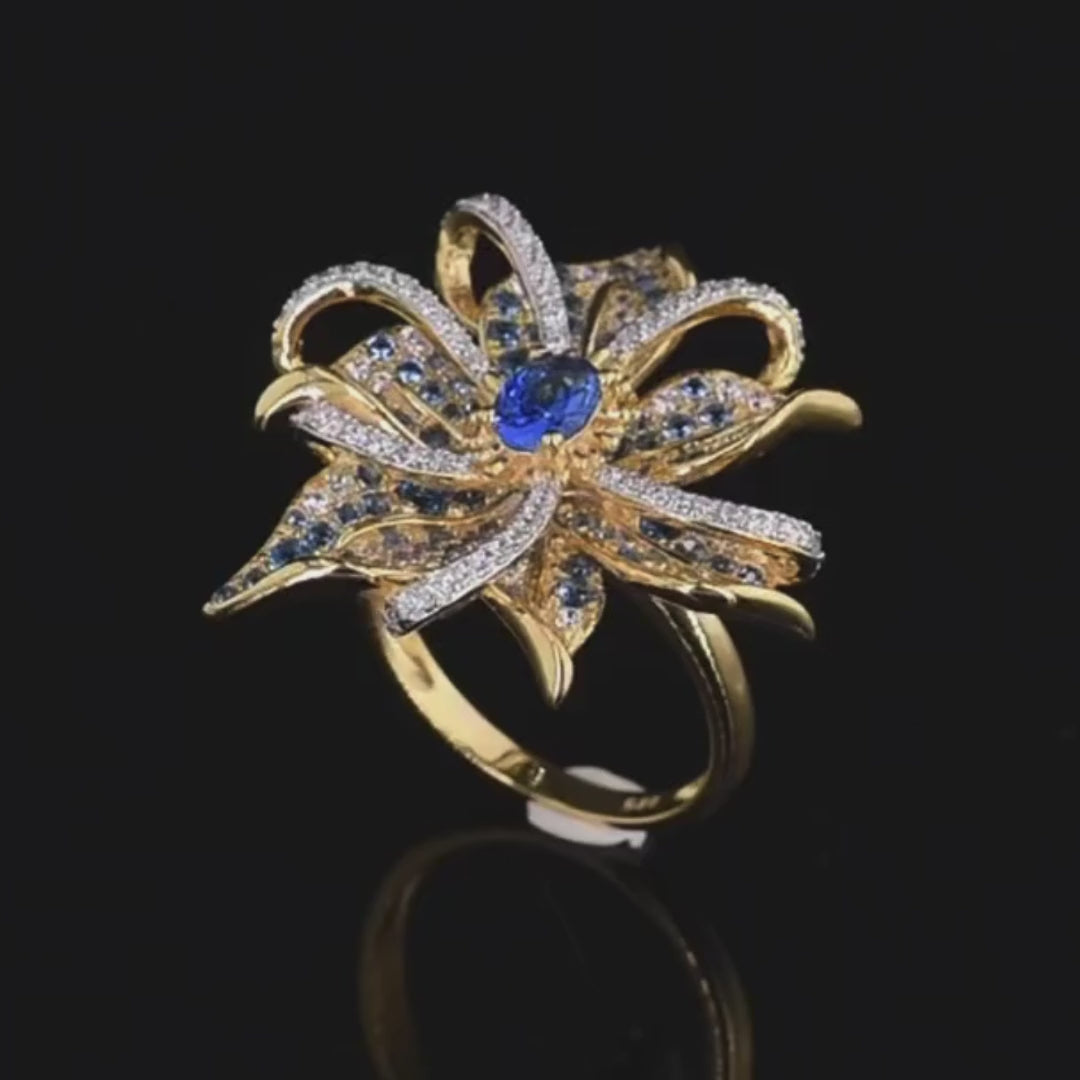 Gold ring in the shape of a flower with pavé blue and white stones and a central oval gem

