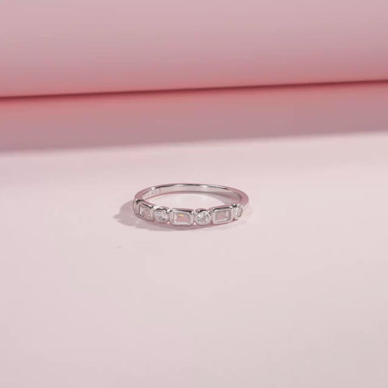 Silver ring featuring alternating round and baguette-cut white stones in a half-band setting.

