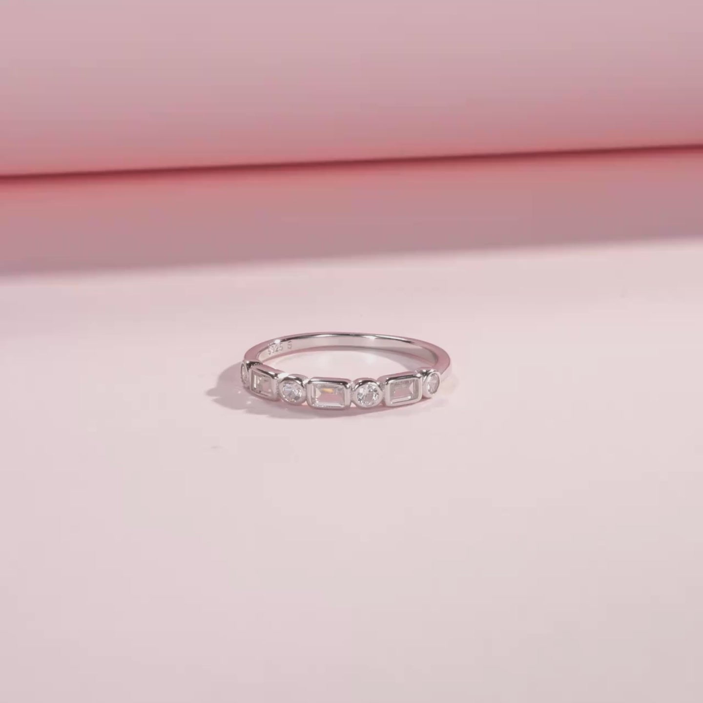 Silver ring featuring alternating round and baguette-cut white stones in a half-band setting.

