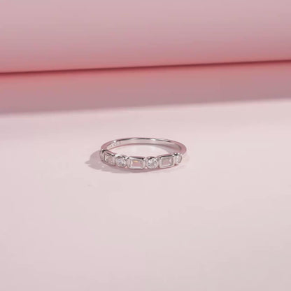 Silver ring featuring alternating round and baguette-cut white stones in a half-band setting.

